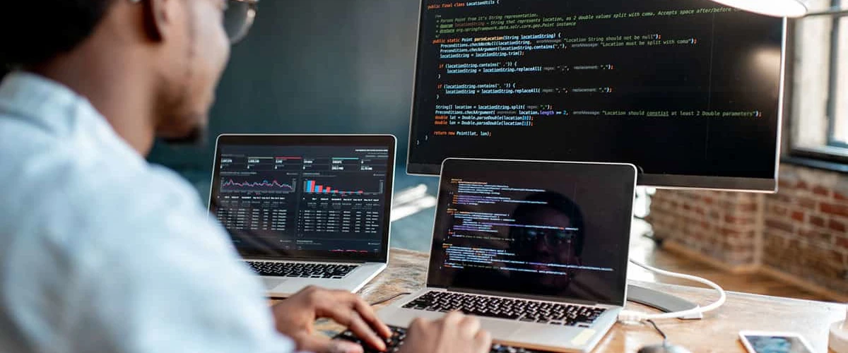 Hombre-programando-en-computadora-y-dos-laptop