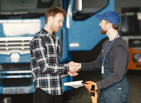 Men shaking hands in front of a truck